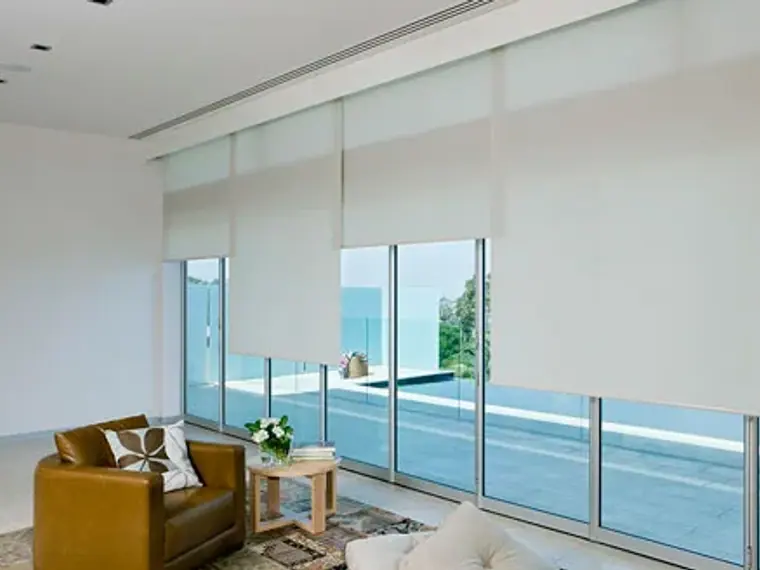 Sala luminosa con cortinas roller translúcidas y vista al mar