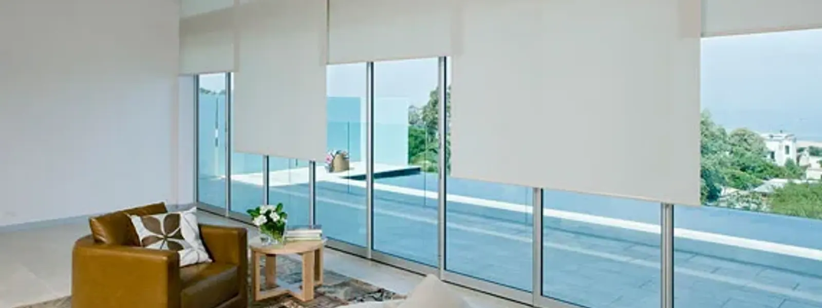 Sala luminosa con cortinas roller translúcidas y vista al mar